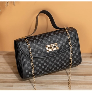 Close-up of black quilted crossbody bag with gold chain strap and turn-lock closure
