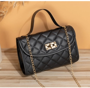 Detail of black quilted leather crossbody bag featuring gold hardware and chain strap