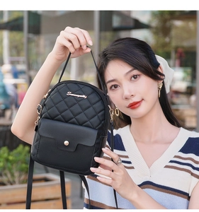 Detail of black mini quilted backpack featuring gold logo and adjustable straps in street setting