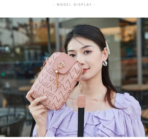 Modèle portant un petit sac à bandoulière rose en cuir PU avec détails couronne et pompon