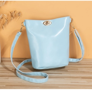 Detail view of light blue PU bucket bag featuring a golden twist lock and metal hardware