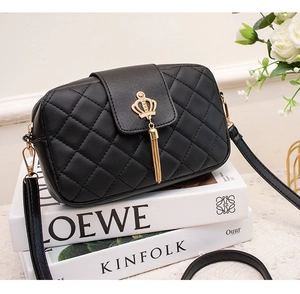 Close-up of black quilted shoulder bag featuring gold crown emblem and tassel detail