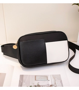 Détail d'un sac bandoulière contrasté noir et blanc avec pendentif rond doré