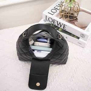 Quilted black handbag with gold hardware and wide strap shown with internal essentials