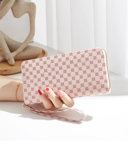 Close-up of pink long wallet with red clover pattern and gold metal zipper detail