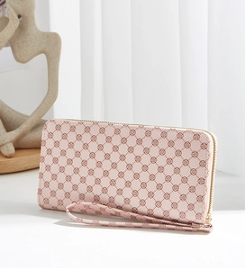 Detail of pink long zip wallet with clover pattern and matching wrist strap on table
