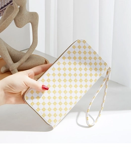 Detailed close-up of a long white clutch with yellow floral print and a wrist strap