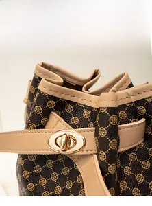 Détail du sac seau avec motif trèfle doré et fermoir rotatif métallique élégant