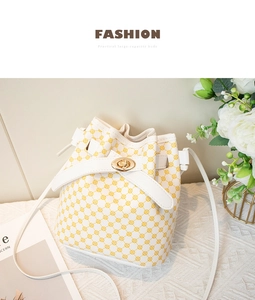Détail du sac seau blanc avec motif floral jaune et fermoir rotatif doré élégant