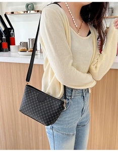 Lifestyle shot of a black crossbody bag with geometric patterns at a cafe setting