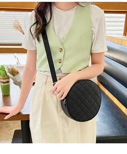 Vue détaillée d'un petit sac rond noir matelassé avec une fermeture éclair dorée
