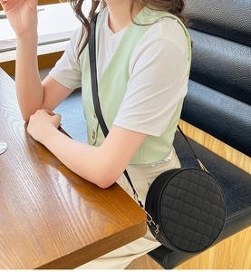 Détail du sac à bandoulière rond matelassé en cuir noir avec fermoir doré