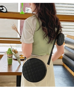 Détail du sac bandoulière rond noir matelassé avec petit porte-monnaie et boucles dorées