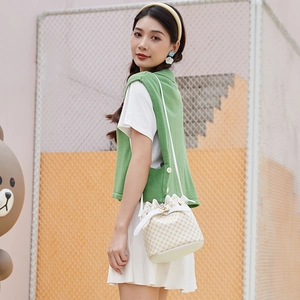 Sac seau chic à carreaux beige avec bandoulière en cuir et fermoir doré sur un modèle