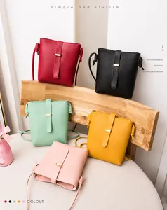 Sacs bandoulière verticaux en cinq couleurs disposés sur une chaise en bois élégante