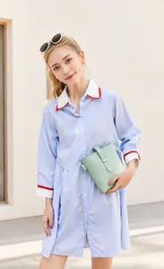 Sac seau en cuir vert menthe porté avec une robe chemise rayée et des lunettes
