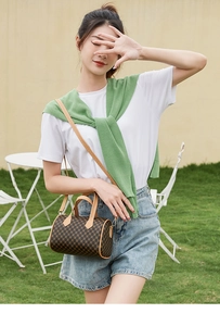 Outdoor shot of a classic brown plaid Boston bag worn as a stylish crossbody handbag