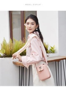 Detailed view of pink PU leather crossbody bag featuring a golden cartoon charm and zip