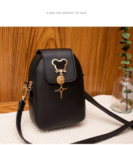 Detail of black leather phone bag with golden mouse charm and star pendant on knit mat