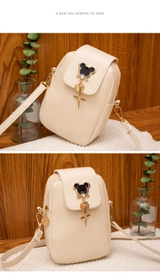 Detailed view of cream crossbody phone bag with Mickey metal charm and smooth PU texture