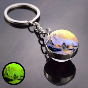 Luminous Christmas keychain with snowy cabin scenery and glowing green effect in dark