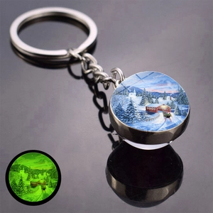 Glow-in-the-dark double-sided glass keychain with a snowy winter scene and green luminescence