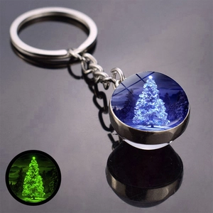 Macro detail of a luminous Christmas keychain showing a snowy tree and green glow effect