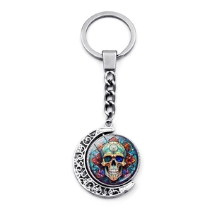 Detail of silver crescent moon keychain featuring a colorful sugar skull design insert