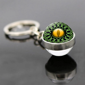 Detailed view of Dragon Eye keychain with glass dome and golden pupil on a black surface