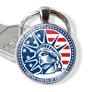 Detail of metal keychain featuring Statue of Liberty and USA flag on a white background
