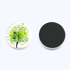 Detail view showing front and back of the tree of life glass magnet on a white surface