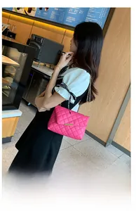 Dettaglio della borsa a tracolla trapuntata rosso rosa con chiusura in oro e catena