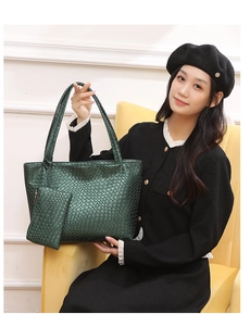 Detalle de bolso tote trenzado verde oscuro con estuche a juego sobre un sofá amarillo
