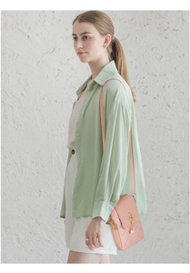 Pink quilted crossbody phone bag with gold crown pendant shown on female model