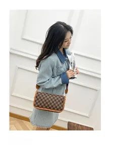Detail of checkered brown crossbody bag with wide strap on model in French style setting