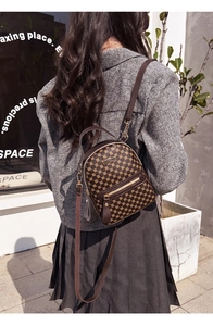 Outdoor back view of a brown vintage mini backpack with gold geometric pattern and thin straps