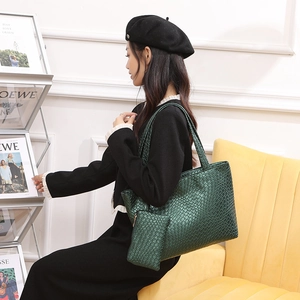 Elegante conjunto de bolso tote tejido verde oscuro con sobre a juego en una modelo