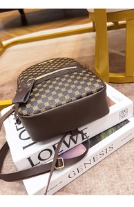 Detail of brown vintage PU leather backpack with gold clover pattern and metal zippers