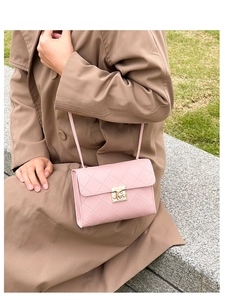 Outdoor shot of a pink quilted shoulder bag with a gold metal lock on a female model