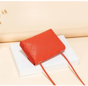Detailed side view of orange quilted leather bag with gold hardware and slim strap