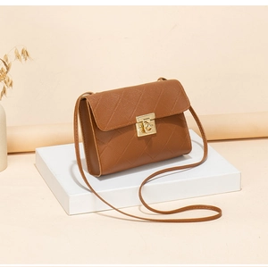 Detailed view of brown quilted crossbody bag with gold twist lock on minimalist stand