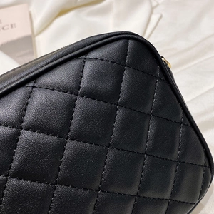 Detailed close-up of premium black diamond quilted leather on a stylish chain handbag