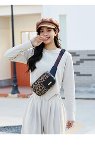 Leopard print waist bag with black leather trim and adjustable strap shown in street style