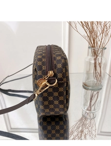 Macro shot of brown crossbody camera bag with clover pattern and gold metal hardware