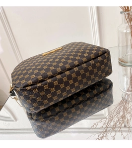 Macro shot showing the vintage brown pattern and gold logo detail of the camera bag