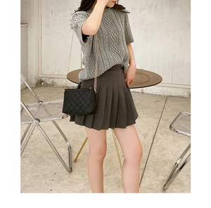 Modern lifestyle view of a quilted chain crossbody bag styled with a pleated skirt