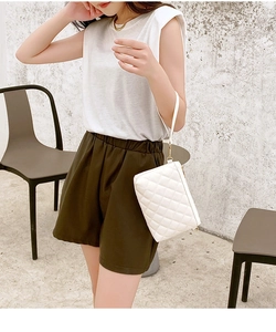 Detailed view of white quilted square bag texture with golden metal buckles and zipper