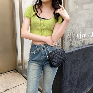 Chic black quilted crossbody bag with gold chain strap worn by a model in casual style