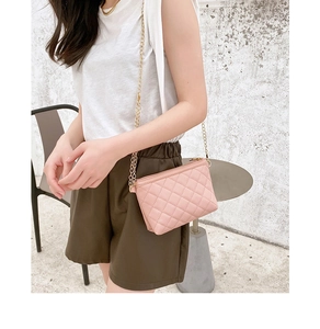 Close-up of pink quilted crossbody bag with gold chain strap and leather texture