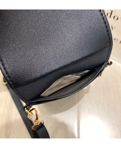 Close-up of black leather phone bag showing golden lobster clasp and back pocket detail